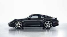 a black porsche sports car parked in a white studio area with no one around it