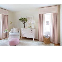 a white chair sitting next to a window in a room with pink drapes on the windows