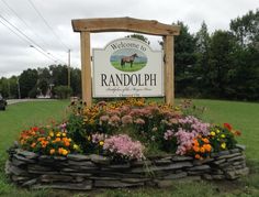 the welcome sign to randyoph is surrounded by colorful flowers and rocks in front of a grassy field