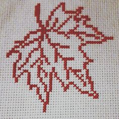 a cross stitch pattern with a red leaf on it