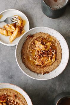 two white bowls filled with oatmeal and bananas on top of a table