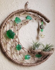 an air plant hanging on the wall next to a piece of string and some glass beads