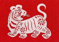 a white paper cut out of a tiger on a red background with the word's symbol