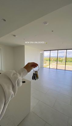 a person holding keys in their hand while standing next to a wall with large windows