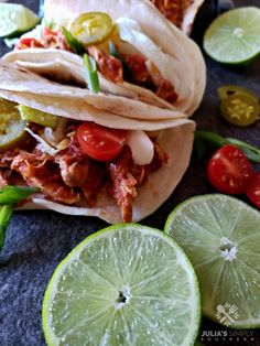 three tacos with meat, tomatoes and limes