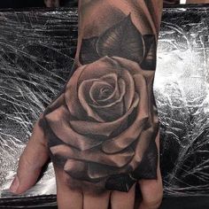 a black and white rose tattoo on the left hand