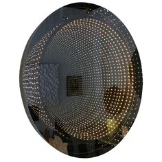 a circular mirror with lights on it reflecting the reflection of a person's face