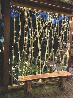 a bench sitting on top of a wooden deck next to a fence covered in lights