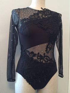 a female mannequin wearing a black bodysuit with sheer sleeves and lace detailing