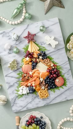 a christmas tree made out of fruits and vegetables on a marble platter next to other holiday decorations