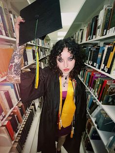 a woman wearing a graduation cap and gown in a library with bookshelves behind her