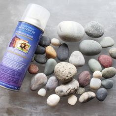 a bottle of sunscreen next to some rocks and stones on the ground with it's lid open