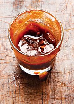 a glass filled with liquid sitting on top of a wooden table