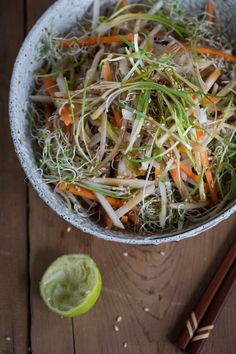 a bowl filled with vegetables next to chopsticks on top of a wooden table