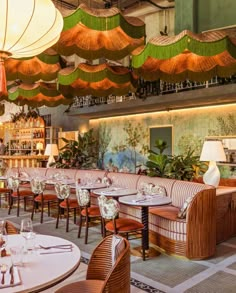 the interior of a restaurant with tables, chairs and umbrellas hanging from the ceiling