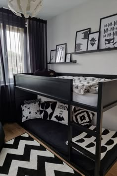 a bunk bed with black and white pillows in a room that has pictures on the wall