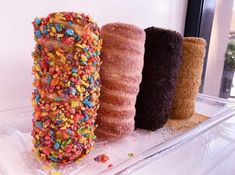 three donuts with sprinkles are on a clear shelf next to each other