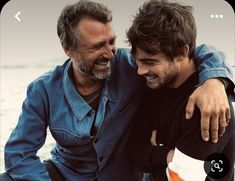 two men sitting next to each other on a boat looking at the camera and smiling