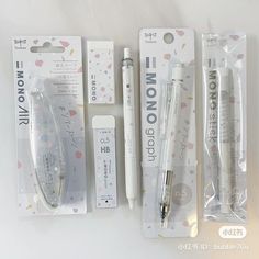 three pens and two erasers in packaging on a white surface with other items around them