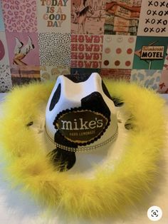 a hat with yellow feathers on top of a white table next to posters and signs