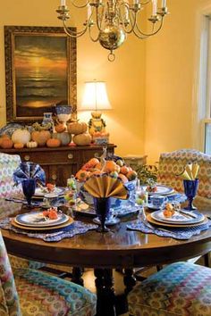 the dining room table is set with blue and white dishes, place settings, and candles