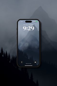 an iphone with the clock displayed on it's screen and mountains in the background