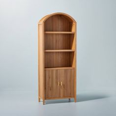 a wooden bookcase sitting on top of a white floor next to a blue wall