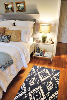 a white bed sitting next to a black and white rug on top of a wooden floor