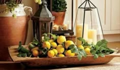 a tray filled with lemons and candles on top of a table next to potted plants