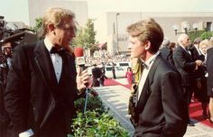 two men in tuxedos are talking to each other on the red carpet at an event