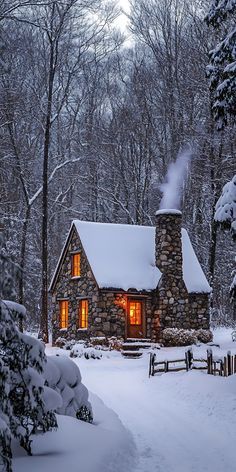 a cabin in the woods with snow on the ground and trees around it, lit up at night