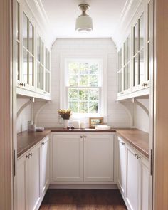 an empty kitchen with white cabinets and wood counter tops on either side of the window