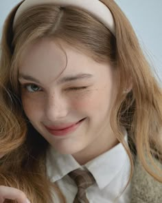 a woman with long hair wearing a white shirt and brown tie smiling at the camera