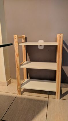 an empty shelf in the corner of a room with tile flooring and light colored walls