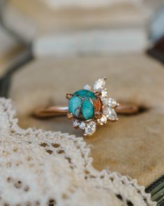 a turquoise stone ring sitting on top of a piece of lace