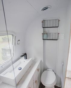 a white toilet sitting inside of a bathroom next to a sink and shower head mounted on the side of a wall