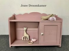 a toy giraffe sitting on top of a pink shelf next to a wall