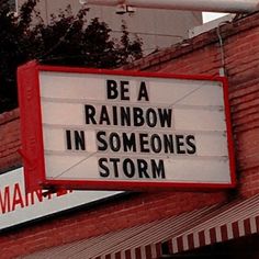 a sign that says be a rainbow in someone's storm on the side of a building