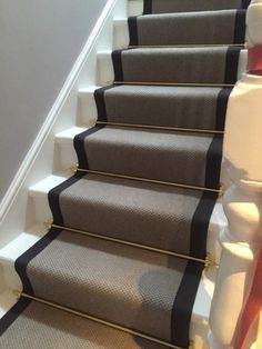 the carpeted stairs are lined with black and white runners