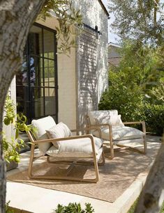 two wooden chairs sitting on top of a patio next to a tree and building in the background