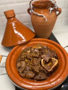 an orange plate topped with meat next to a brown vase and potted planter