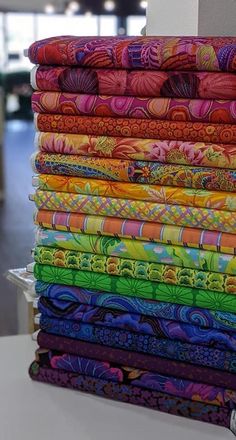 a stack of multicolored cloths sitting on top of a white table next to each other