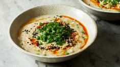 two bowls filled with soup and garnished with green onions on a marble table