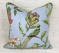 a blue pillow with a green bird and flowers on it