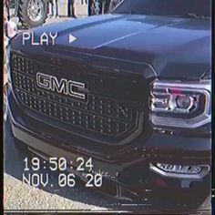 the front end of a black truck parked in a parking lot next to other cars