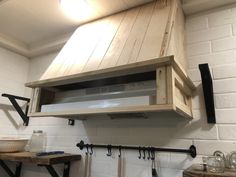 a microwave oven mounted to the side of a white brick wall in a kitchen with hanging utensils