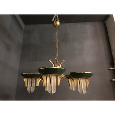 a chandelier hanging from the ceiling in a room with grey walls and gold fixtures