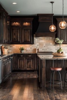 a kitchen with dark wood cabinets and marble counter tops, two pendant lights over the island