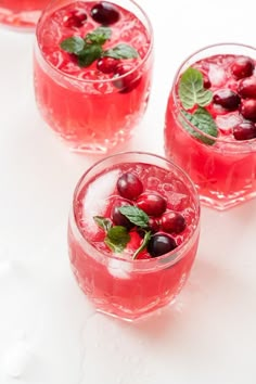 three glasses filled with watermelon and cherries on top of a white surface