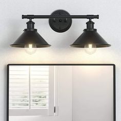 a bathroom mirror with two lights on it and a light fixture above the mirror that is black